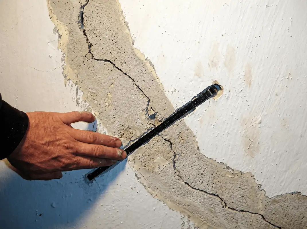 A wall with a large crack is being inspected by a professional in Fort Collins, CO
