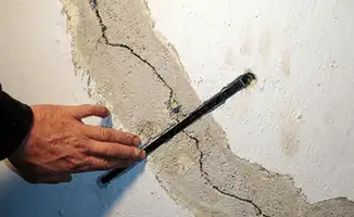 A wall with a large crack is being inspected by a professional in Fort Collins, CO
